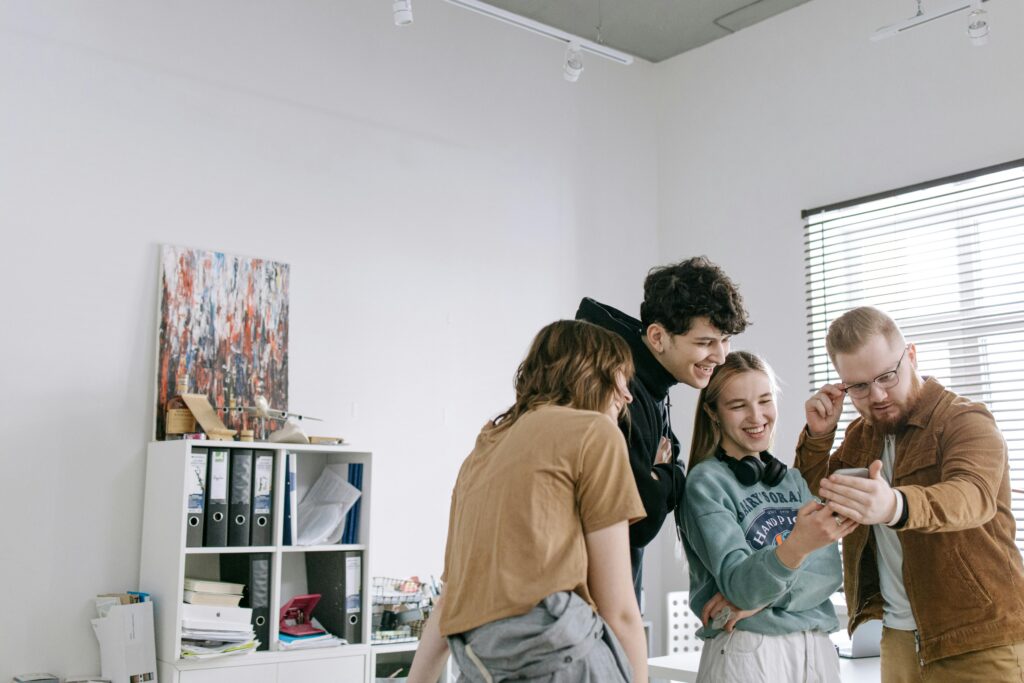 Team of young professionals laughing and collaborating together in a modern office workspace